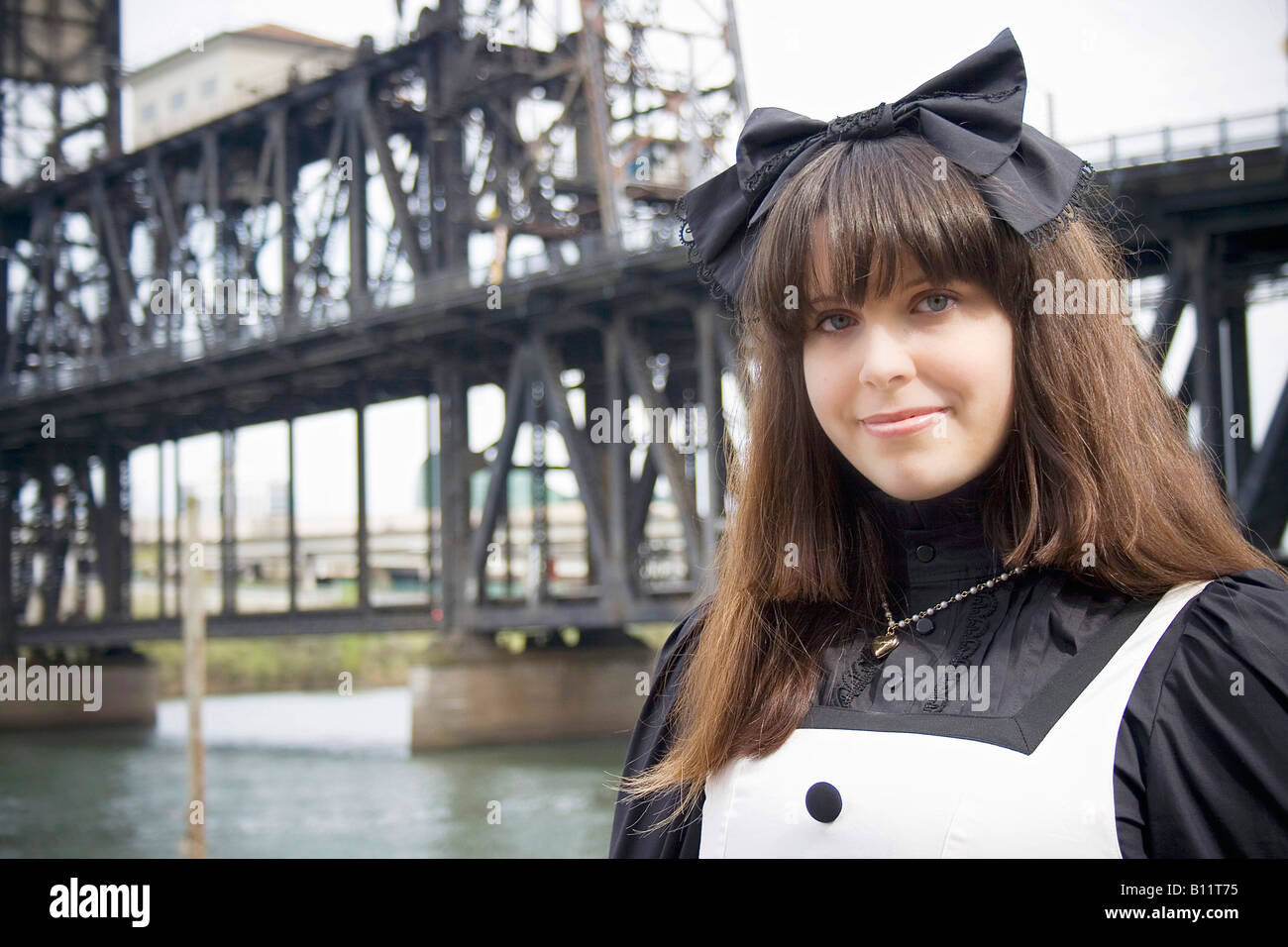 Young woman wearing Japanese lolita fashion standing in front of the Steel Bridge in Portland, Oregon USA Stock Photo