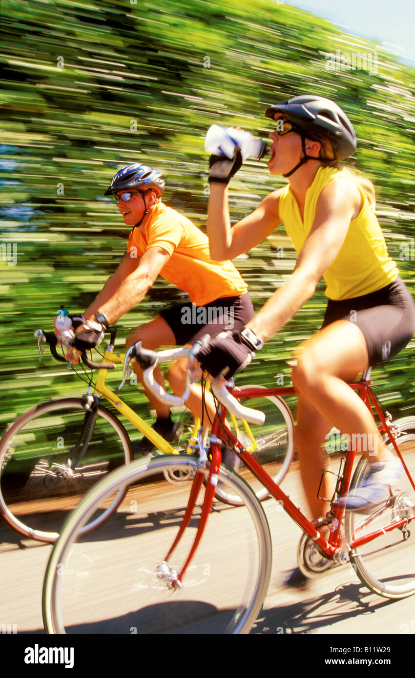 A young couple ride roadbikes at high speed converse and drink from their  water bottles Stock Photo - Alamy