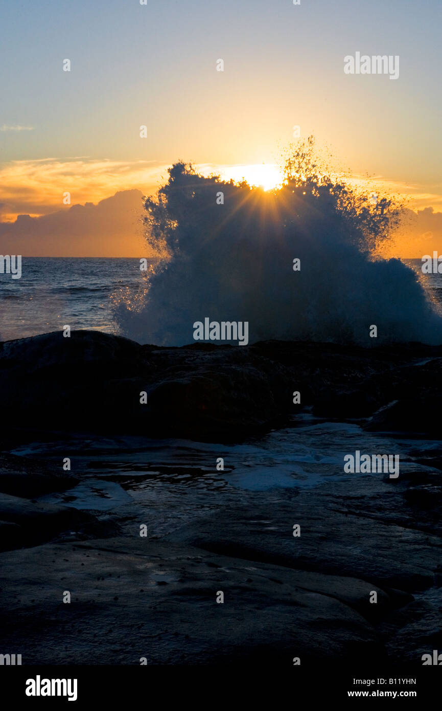 Waves crashing on rocks at dawn Stock Photo