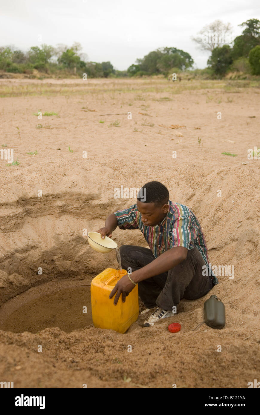Young man pouring drinking water into a container from the water