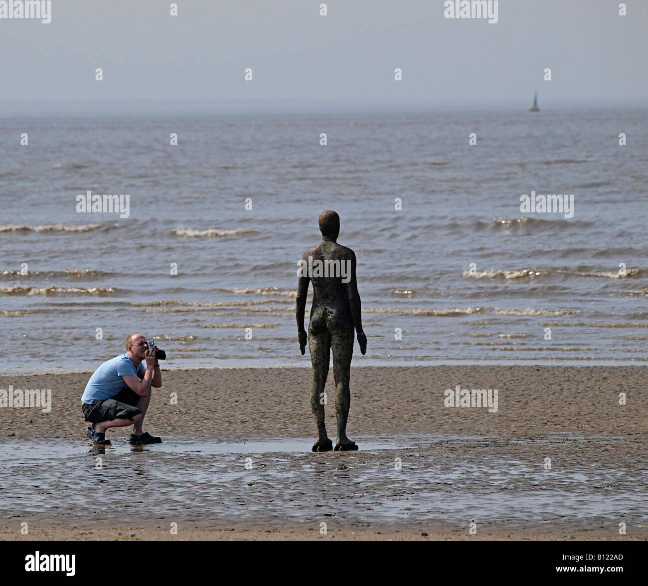 ANTONY GORMLEY SCULPTURED FIGURE ON BEACH AT CROSBY BEING PHOTOGRAPHED