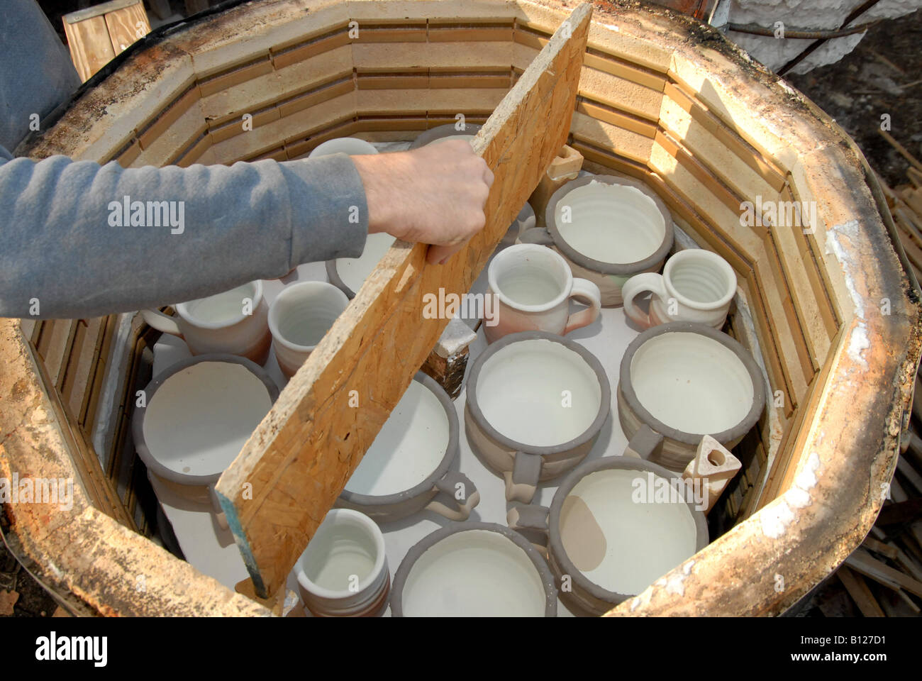 A potter adding a shelf to a kiln being loaded in preparation for