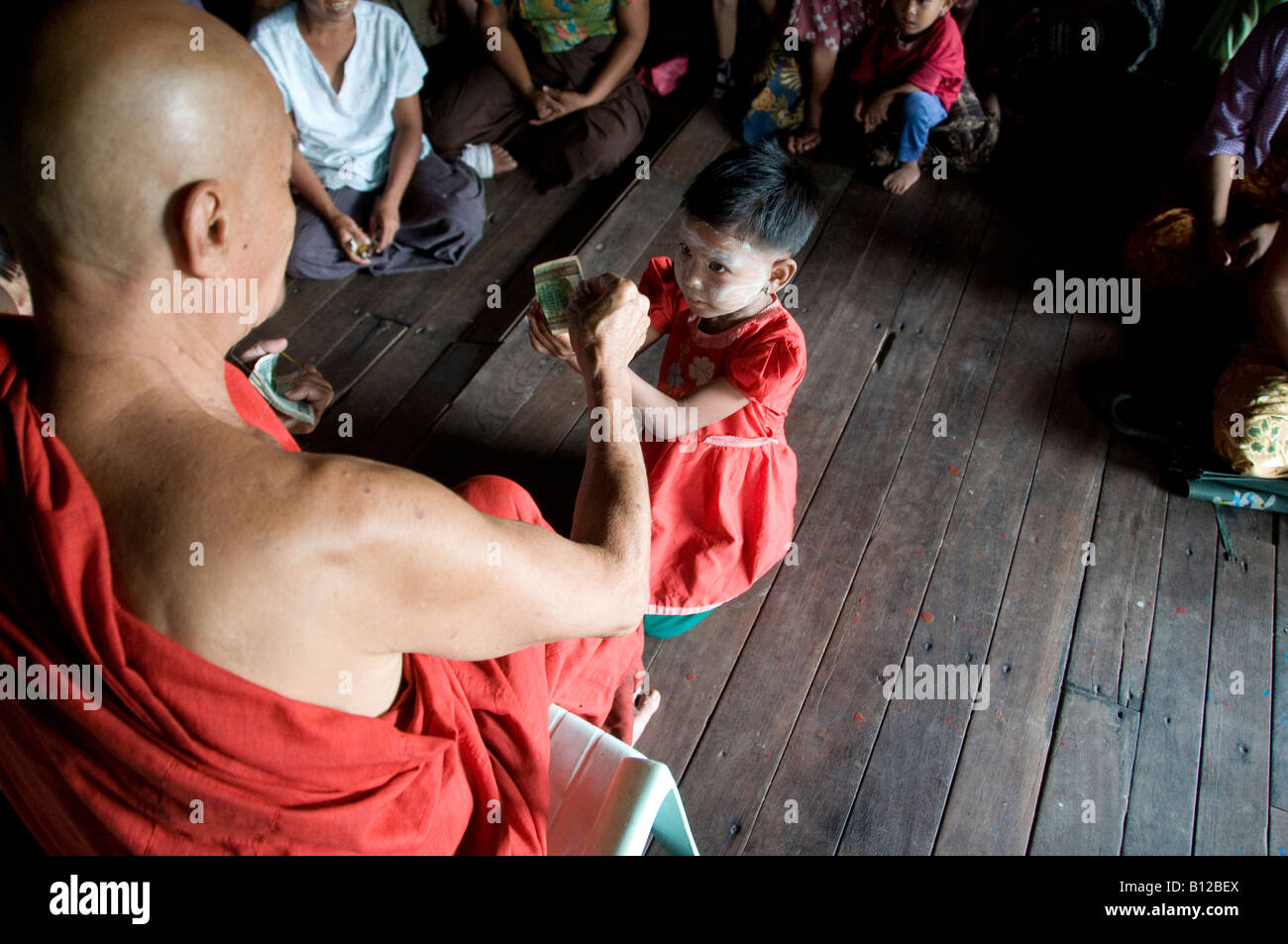 A Buddhist monk gives donation to cyclone affected girl in a monastery in Kyauktan township of Yangon Myanmar, Burma Stock Photo