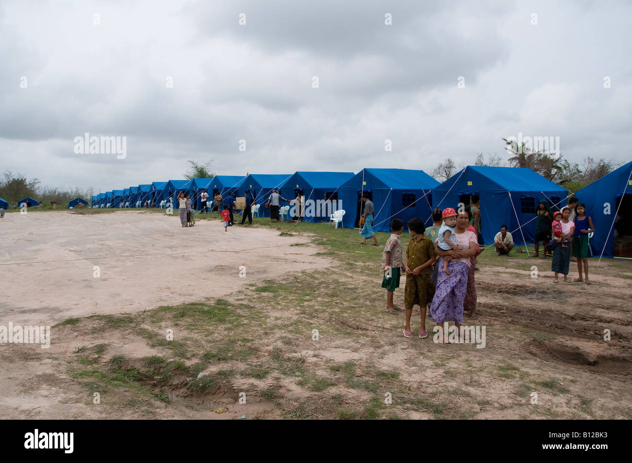 People stand next to their tents at a relief encampment set up by the government for cyclone Nargis victims in Kyauktan township of Yangon Myanmar Stock Photo