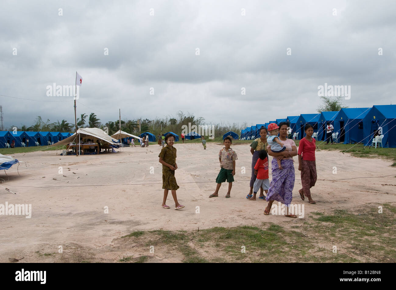 People stand next to their tents at a relief encampment set up by the government for cyclone Nargis victims in Kyauktan township of Yangon Myanmar Stock Photo