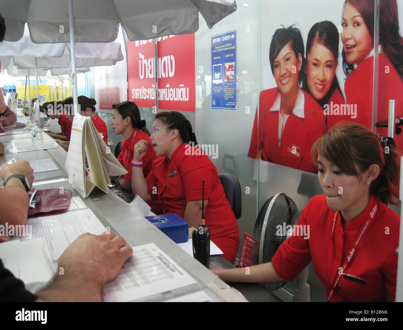 Assistants book flight tickets and handle reservations for customers at Air Asia airline sales counter in Suvarnabhumi International Airport Bangkok Stock Photo