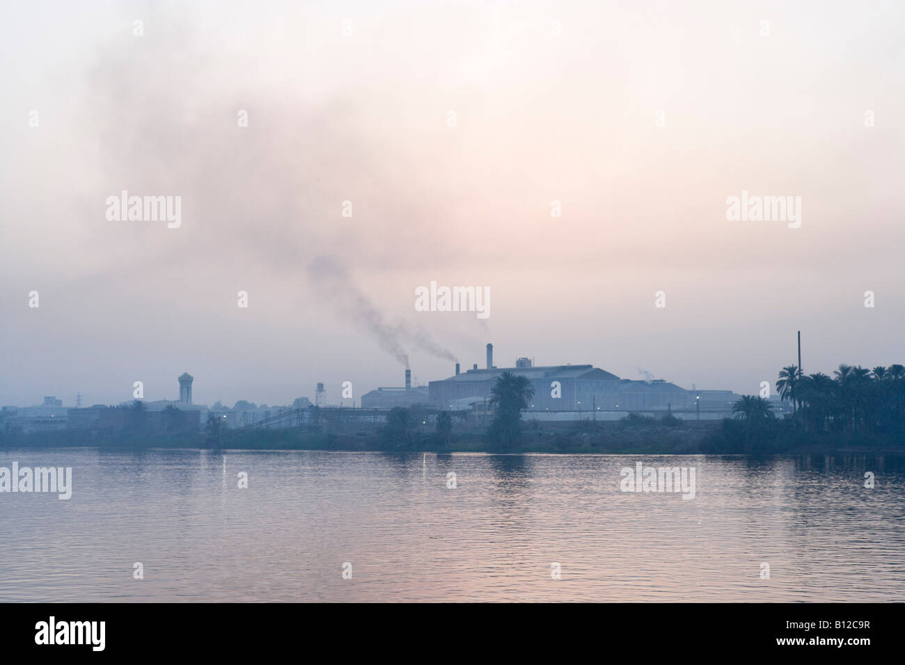 Industrial Pollution from factory on the banks of the River Nile at dawn from deck of Nile Cruiser, Luxor, Nile Valley, Egypt Stock Photo