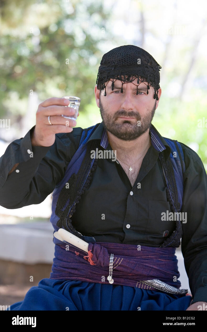 One Cretan man holding shot of Cretan traditional tsikoudia spirit wishing  ''Welcome'' wearing traditional Cretan uniform Stock Photo - Alamy