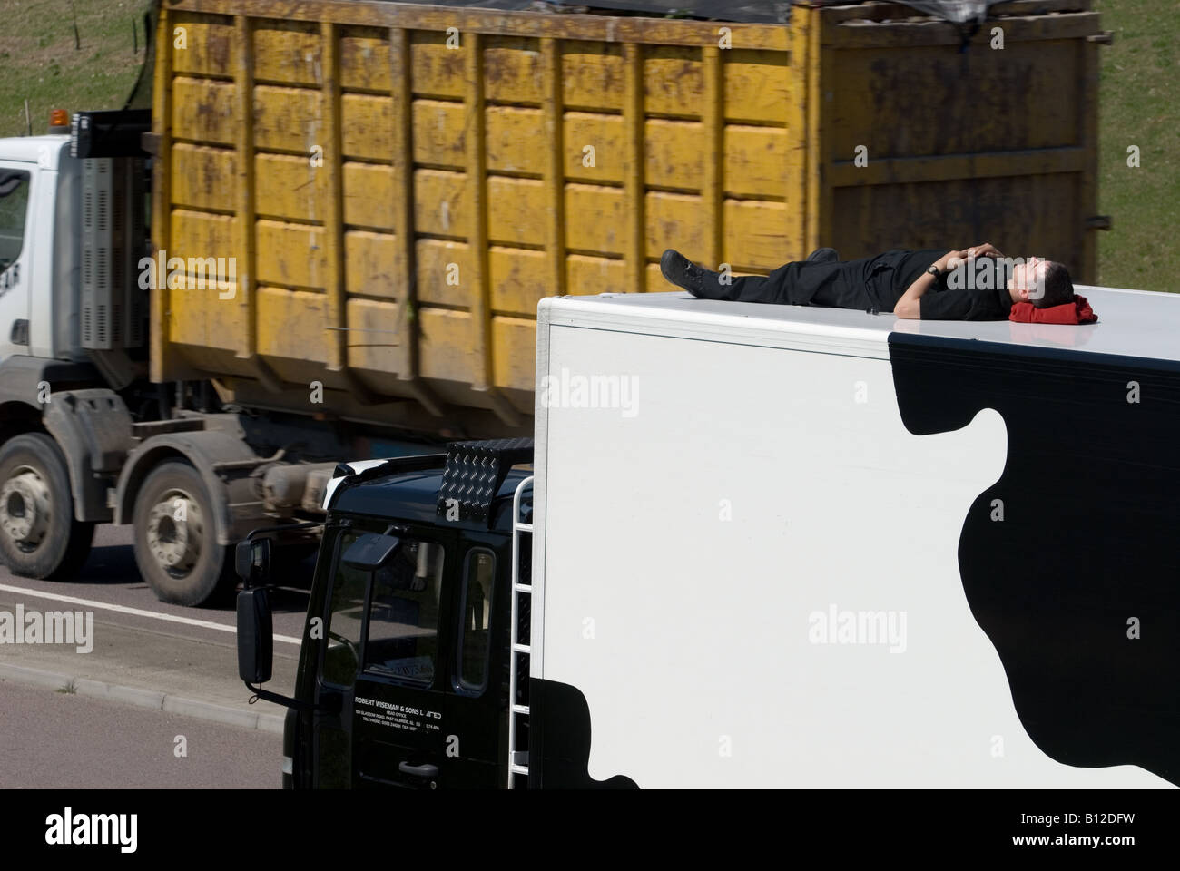 Lorry driver taking a lunch time nap on the top of his lorry in a layby on the A120 near Stansted, Essex, UK. Stock Photo