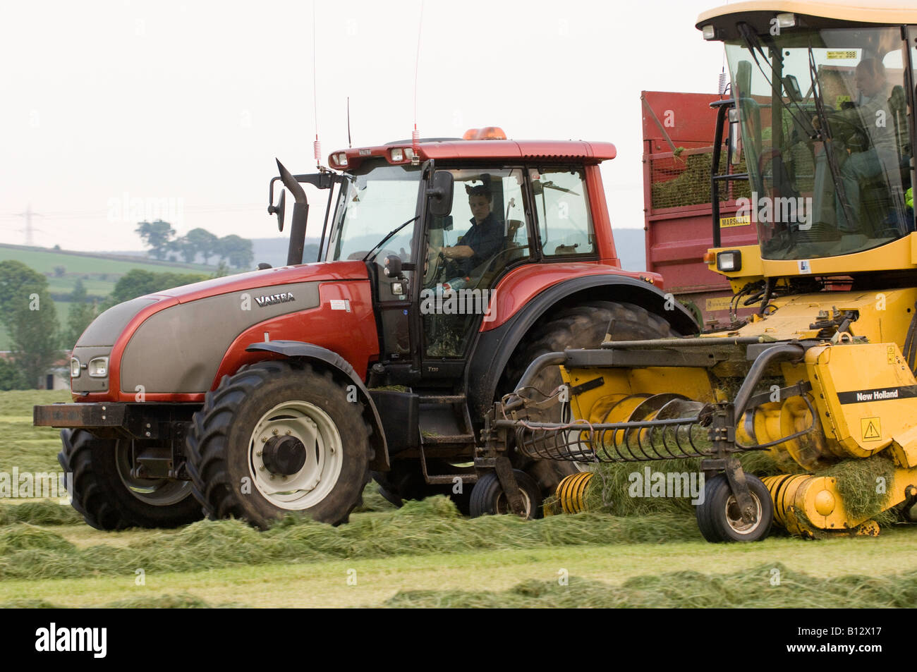 Self propelled forager and Tractor with trailer in field collecting