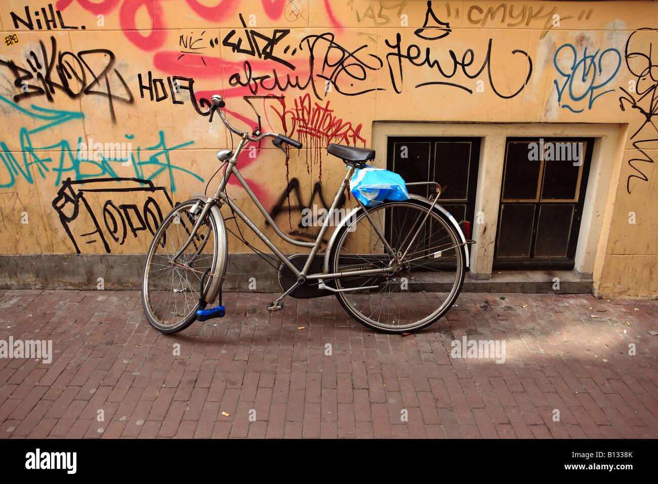Bicycle parked against graffiti covered wall. Stock Photo