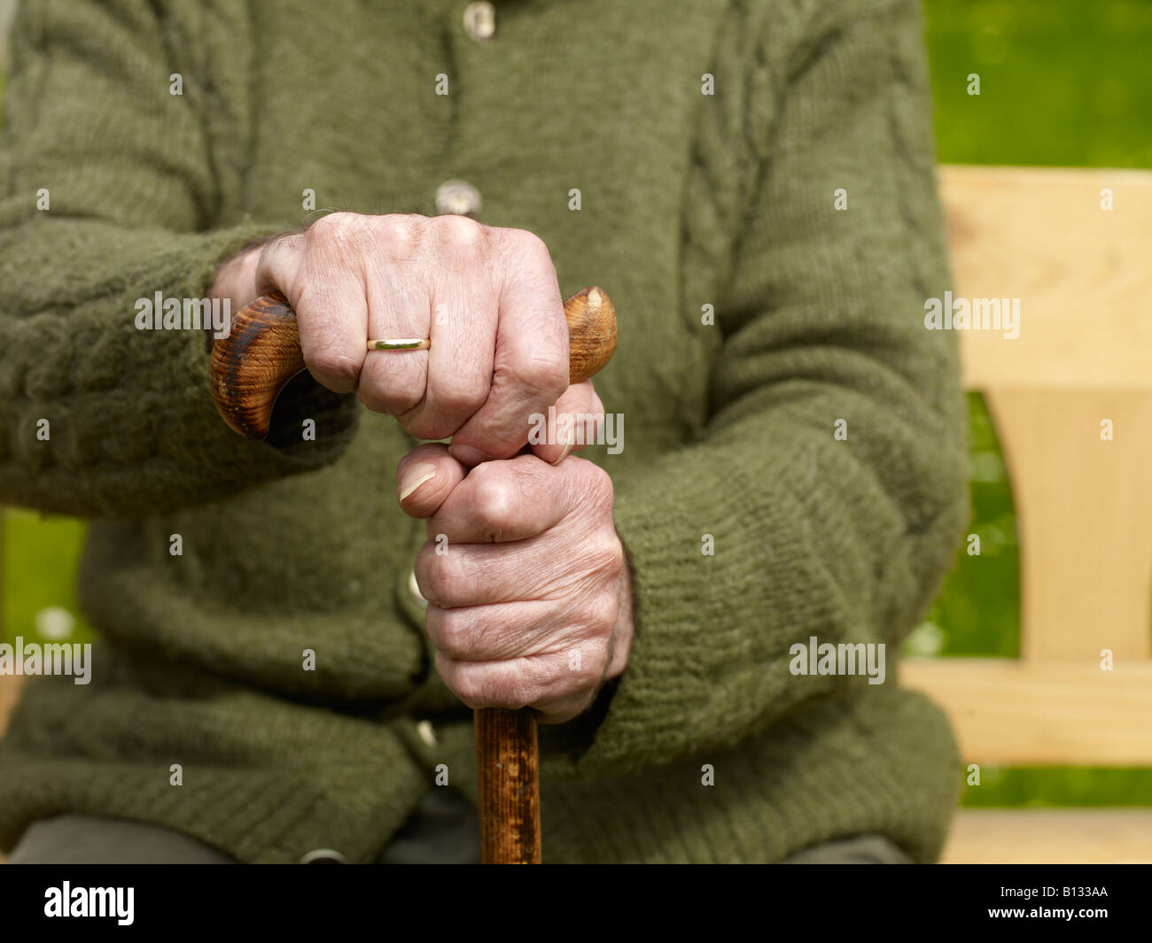 sitting old man with his hands on a cane Stock Photo