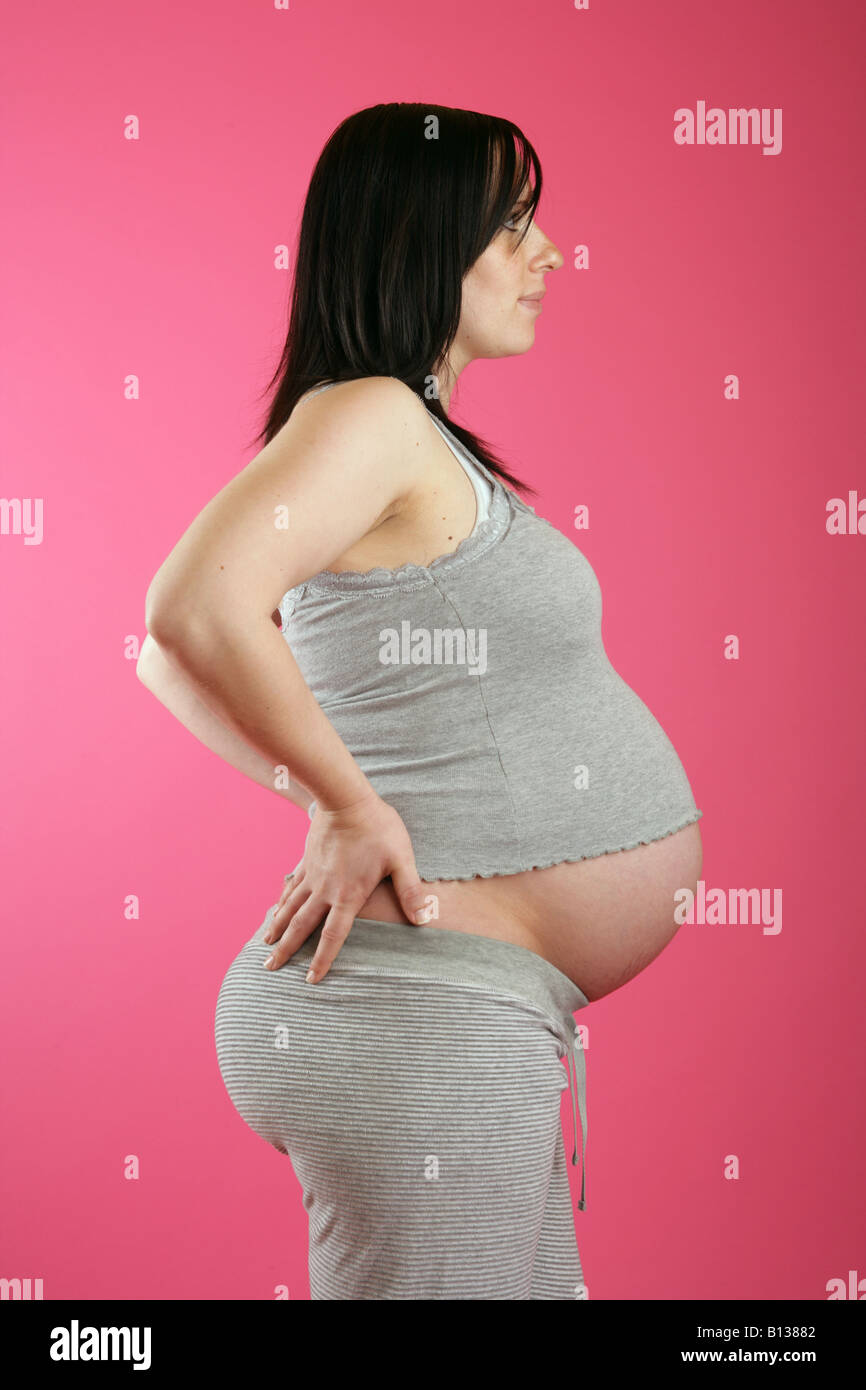 A profile view of a dark haired 38 week (nine months) pregnant woman Stock Photo