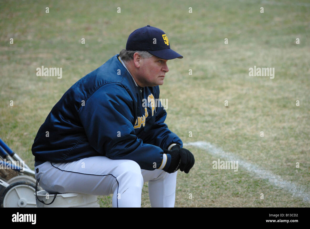 coach sitting and watching his team playing high school baseball Stock