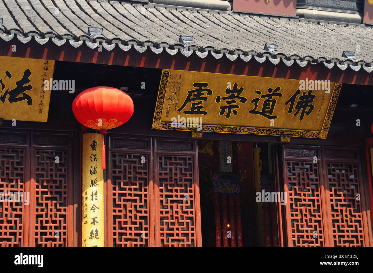 Lattice work elaborately tiled roof red lantern and inscribed motto above entrance to the jade Buddha pavillion Shanghai China Stock Photo