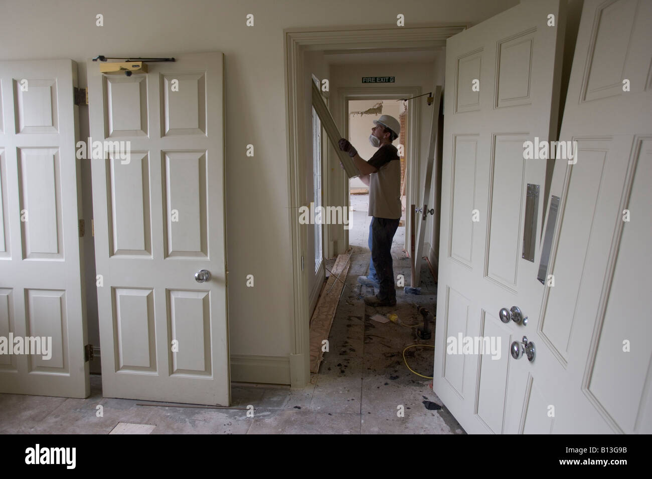 A construction worker removes a piece of molding in a corridor of a demolition site. Stock Photo