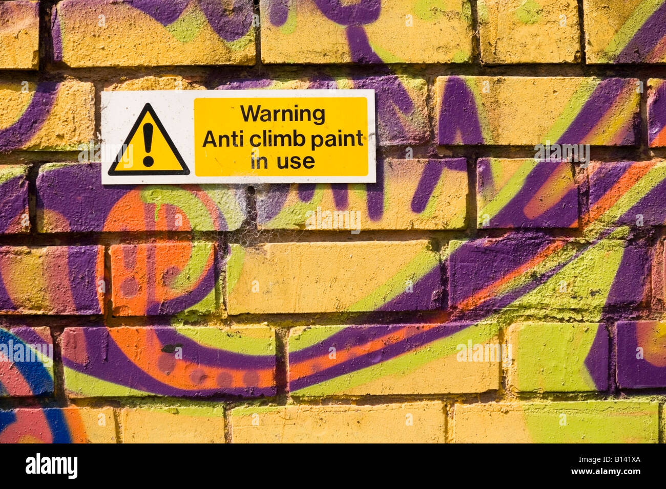 Anti climb paint warning on a graffiti covered wall Stock Photo