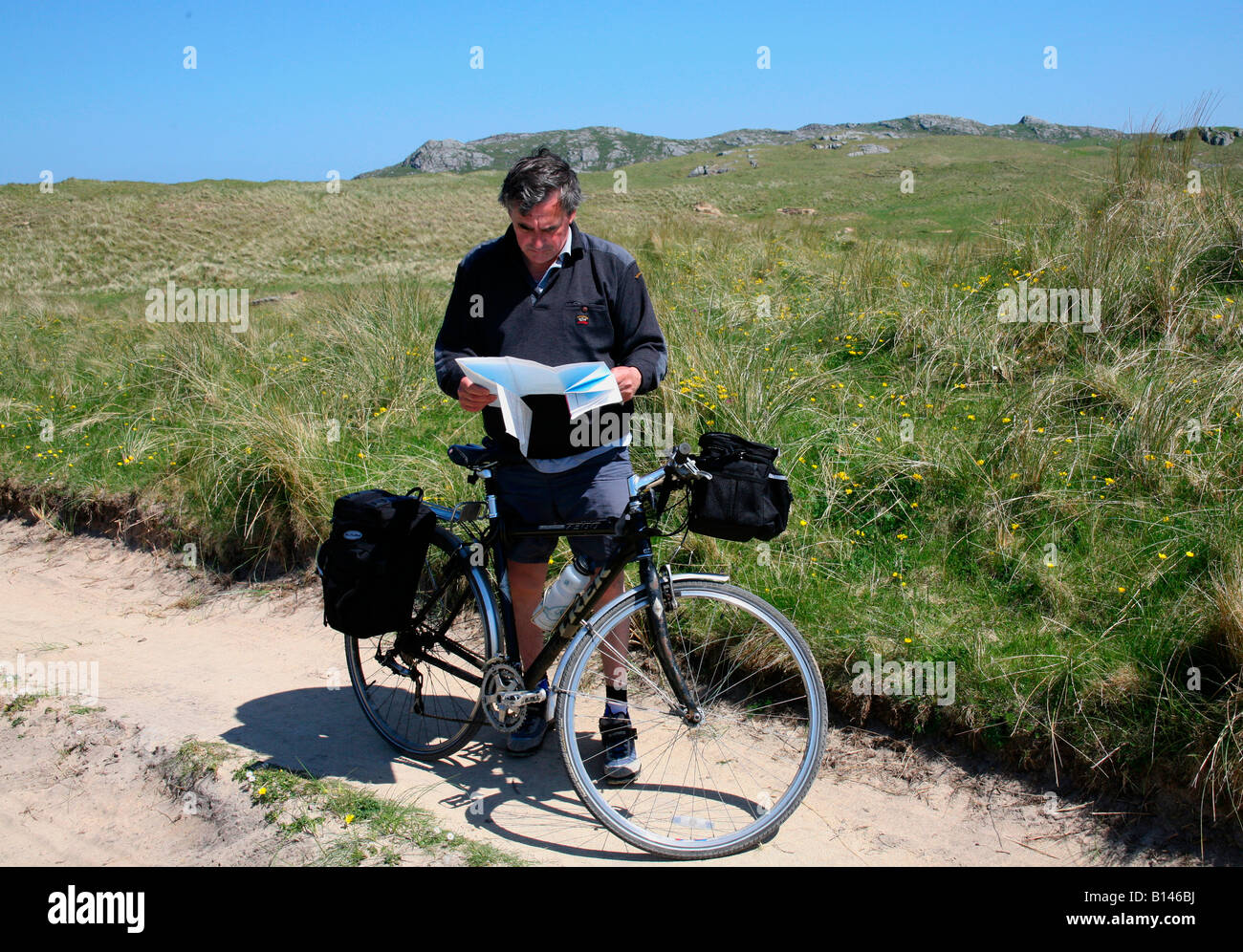 Cyclist checking the map whilst riding through the sand dunes near Hogh Bay Coll Scotland Stock Photo