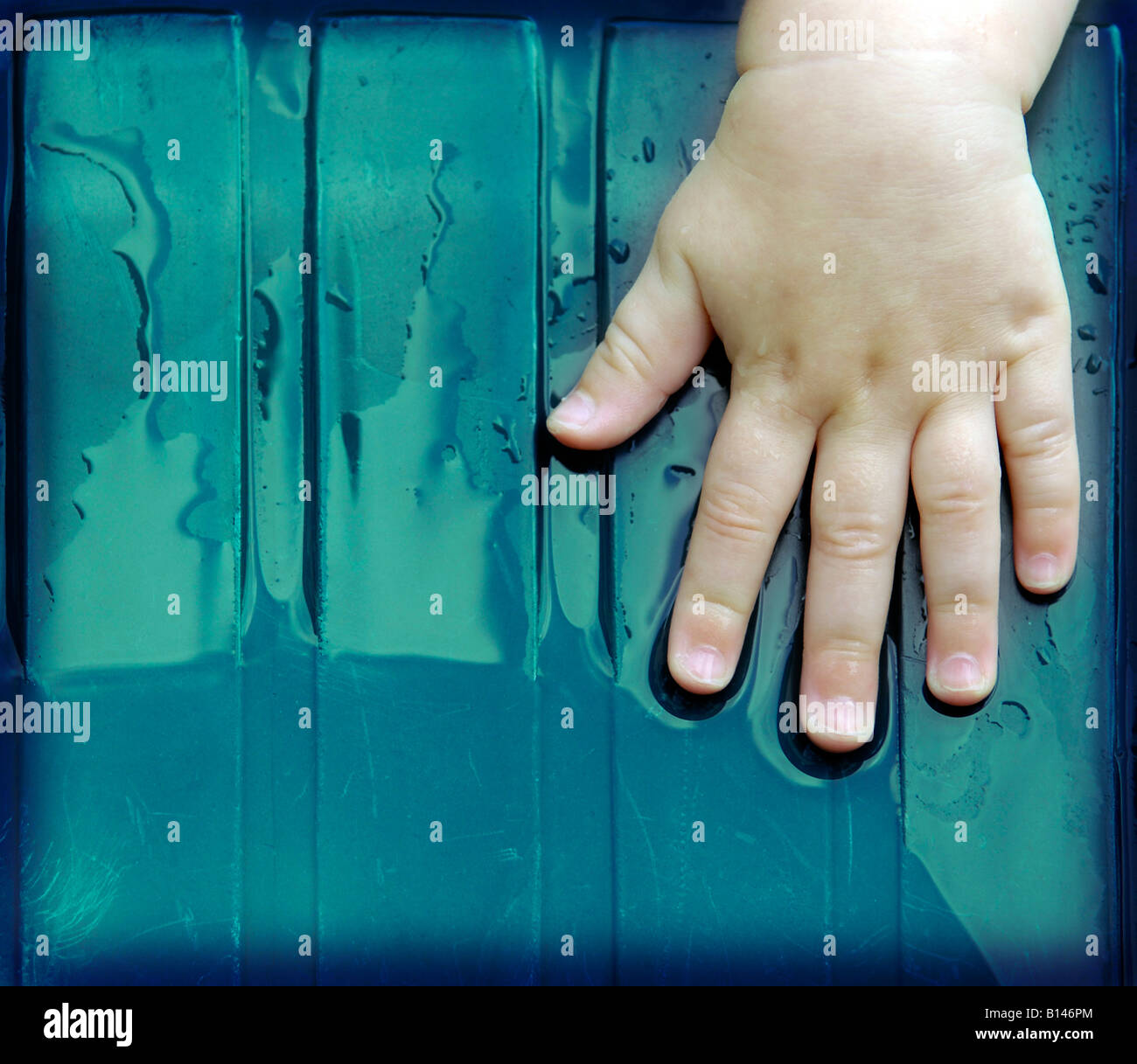 baby hand rain wet green plastic left caucasian Stock Photo