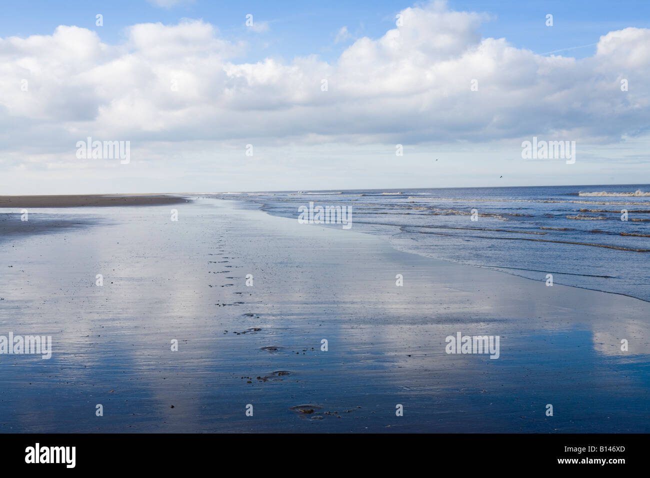 Blue sky and clouds reflected in wet sand on a beach in Lincolnshire Stock Photo