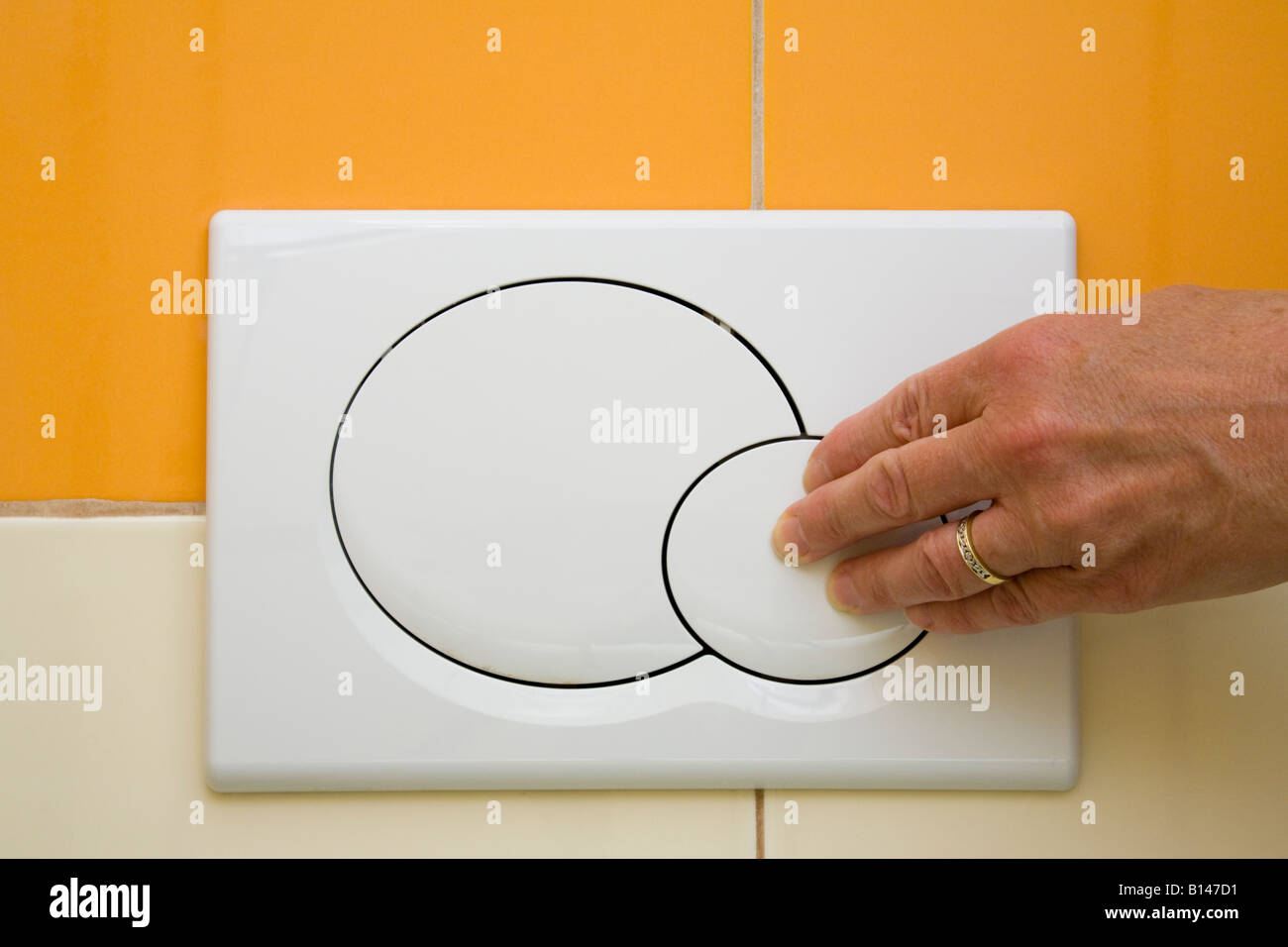 Dual toilet flush with hand pressing small economy flush button in