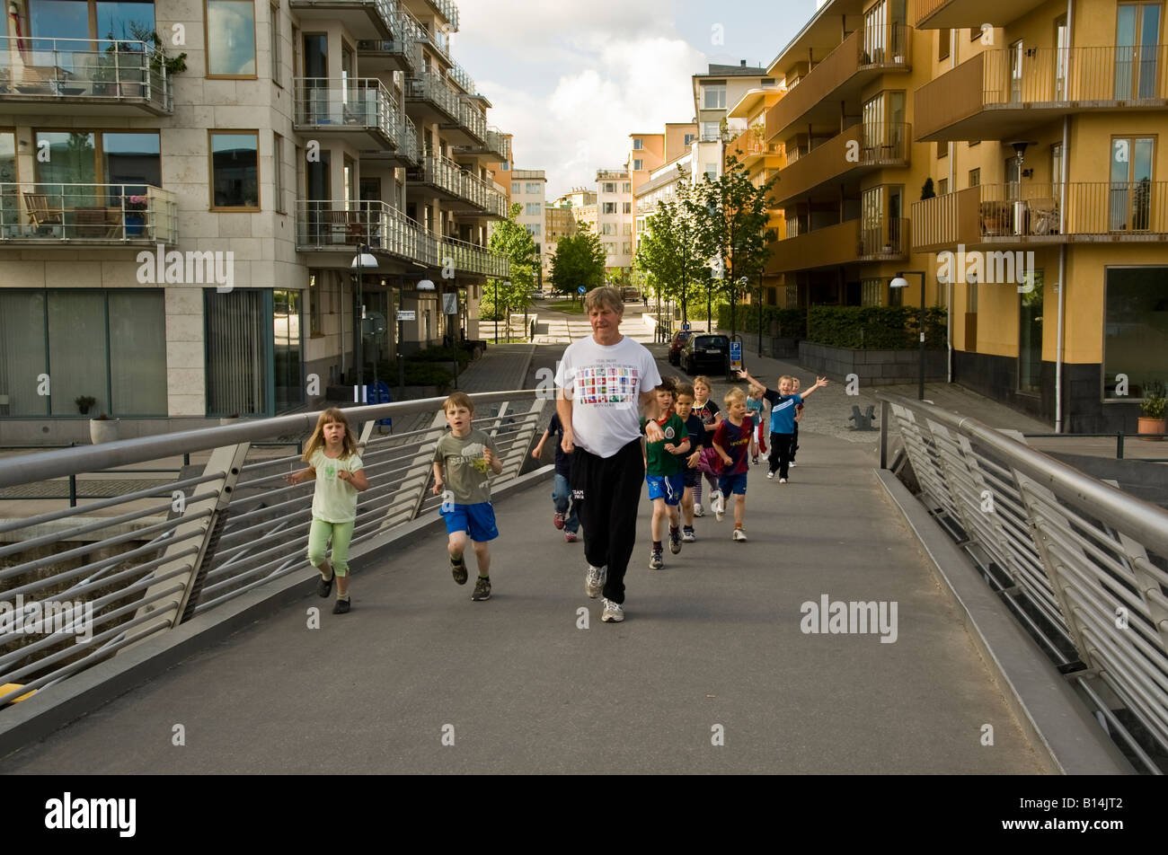Teacher leading a class of very young school children on an exercise run through Stockholm most modern neighbourhood of Hammarby Stock Photo
