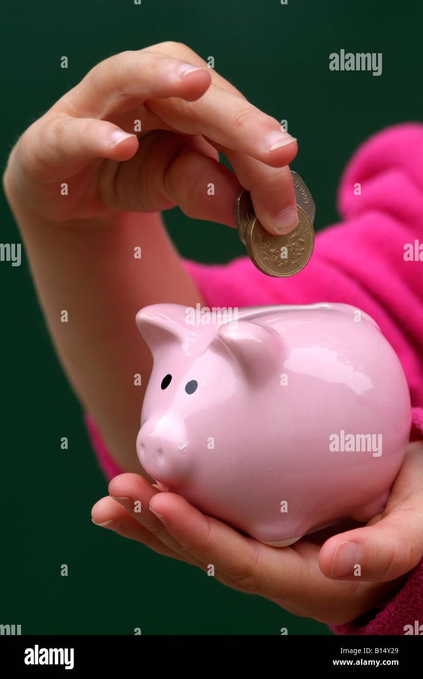 Piggy Bank and childs hand holding money Stock Photo - Alamy