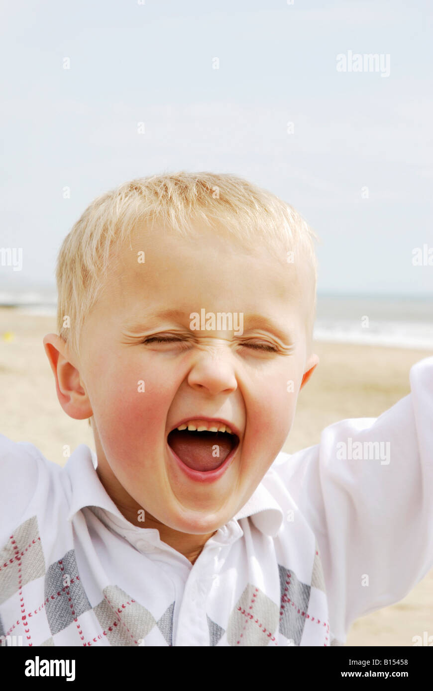 A happy excited 6 year old boy running along the beach shouting with