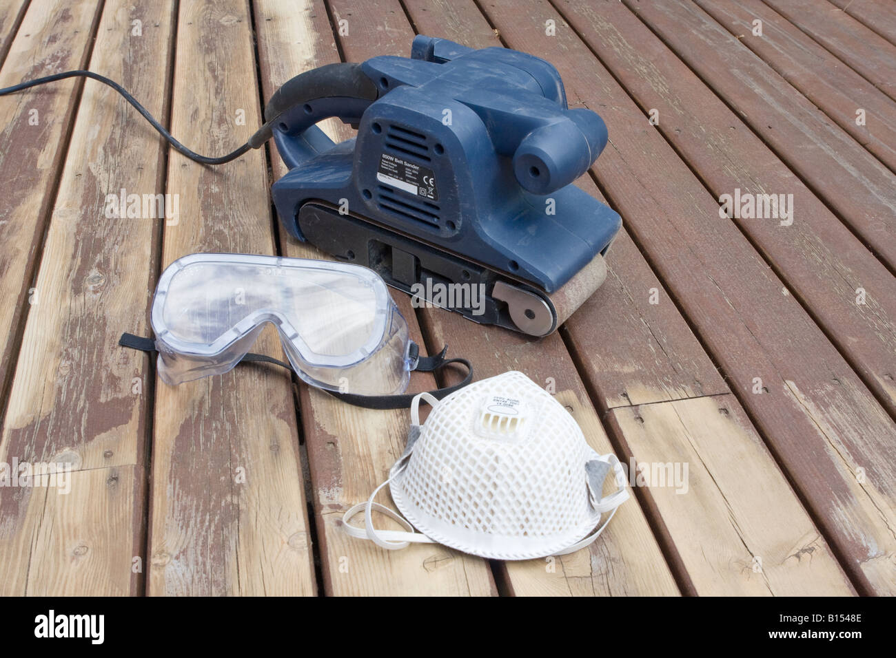 Belt sander on partially sanded wooden decking during renovation with