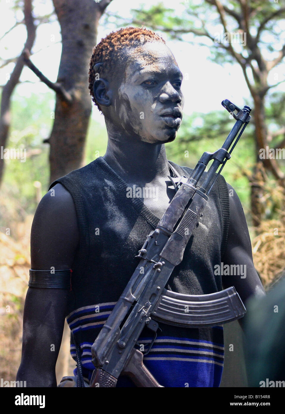 'Price of Independence' - A young Dinka man in a cattle camp near Akot, South Sudan, keeps his AK-47 close. Stock Photo