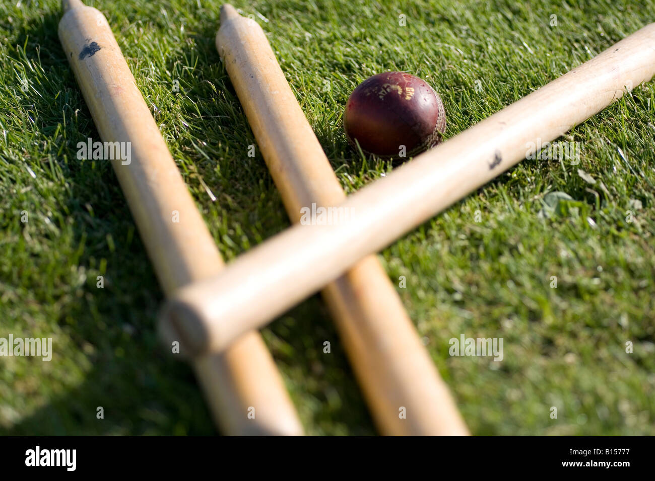 Cricket stumps and ball lie on the grass Stock Photo