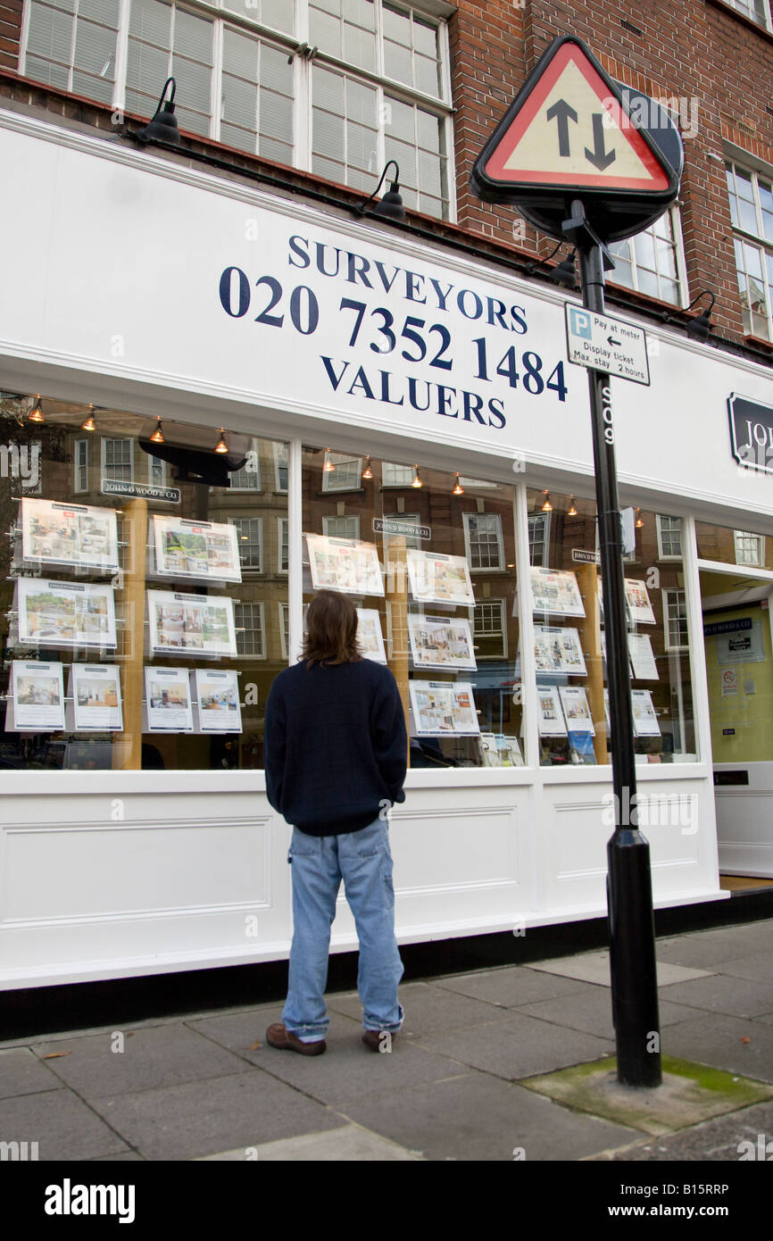 A man looks at house and flat prices in an estate agent window Stock Photo