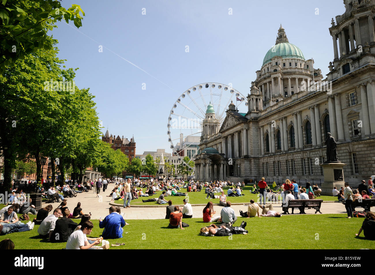 Belfast City hall with crowd sitting relaxing in the May sunshine Stock Photo