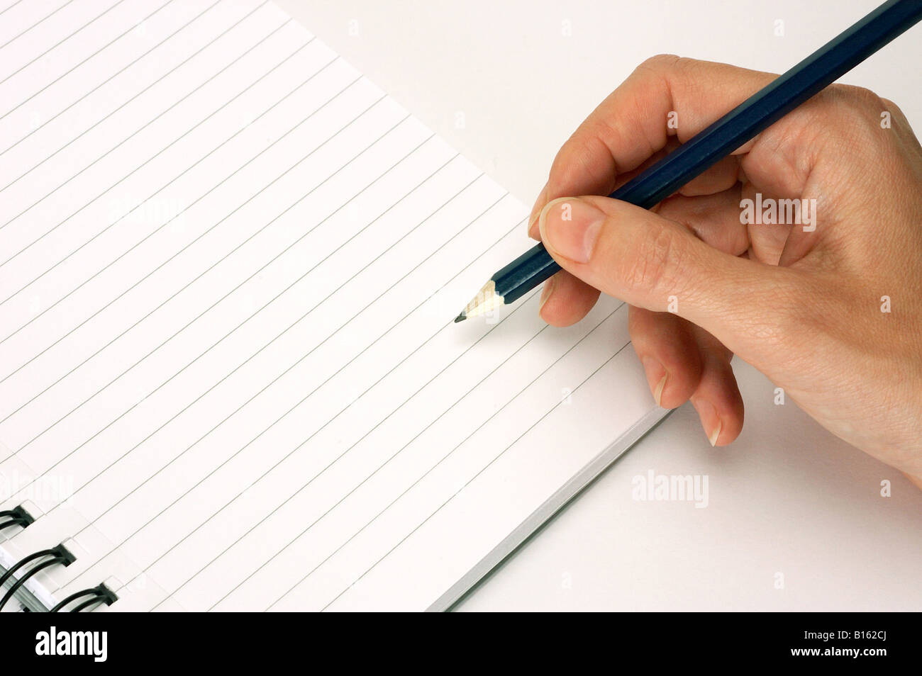 female hand writing with pencil on note pad Stock Photo