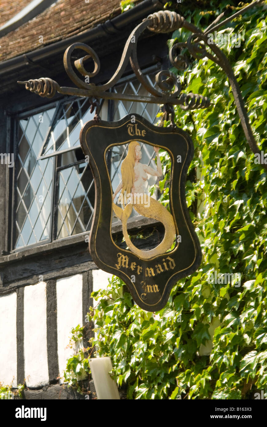 Vertical close up of an old black wrought iron pub sign suspended outside a Tudor building in Rye on a sunny day. Stock Photo