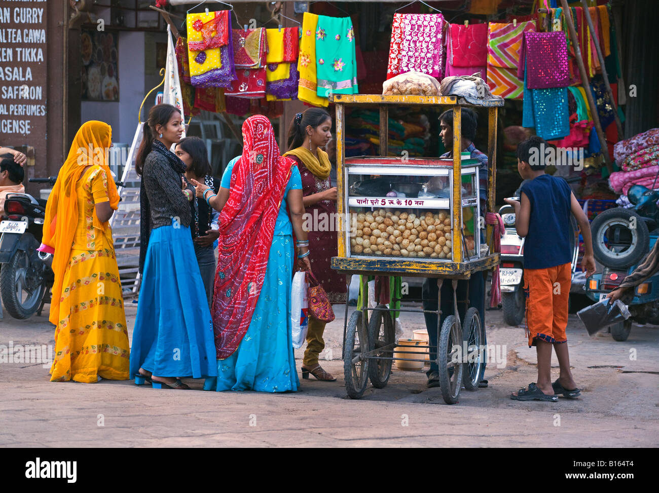 Young girls buy a snack at a food stall in SARDAR MARKET CIRDIKOT in JODHPUR known as the BLUE CITY RAJASTHAN INDIA Stock Photo