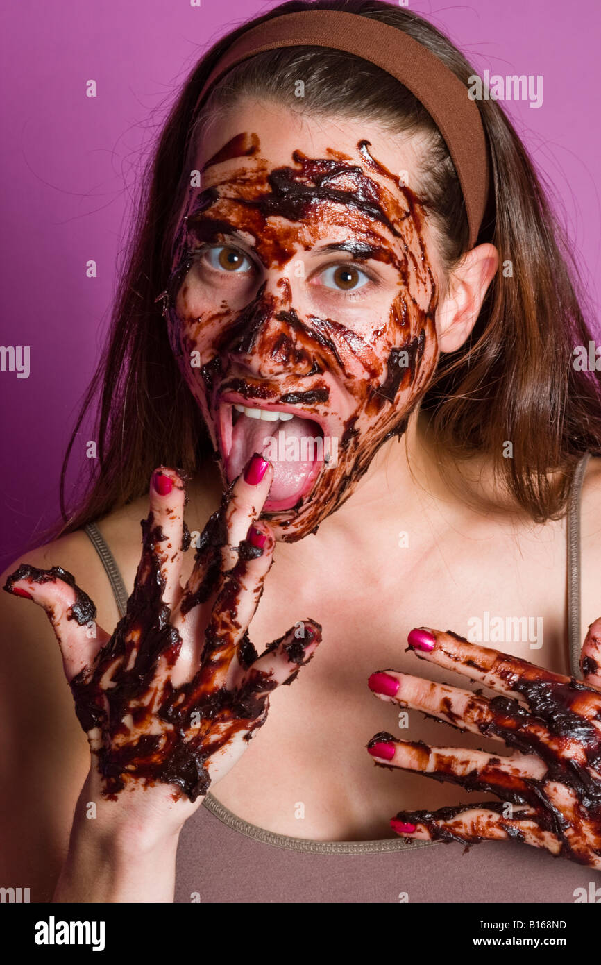 Young woman covered with chocolate eating a piece of cake MODEL and LOCATION RELEASED Stock Photo