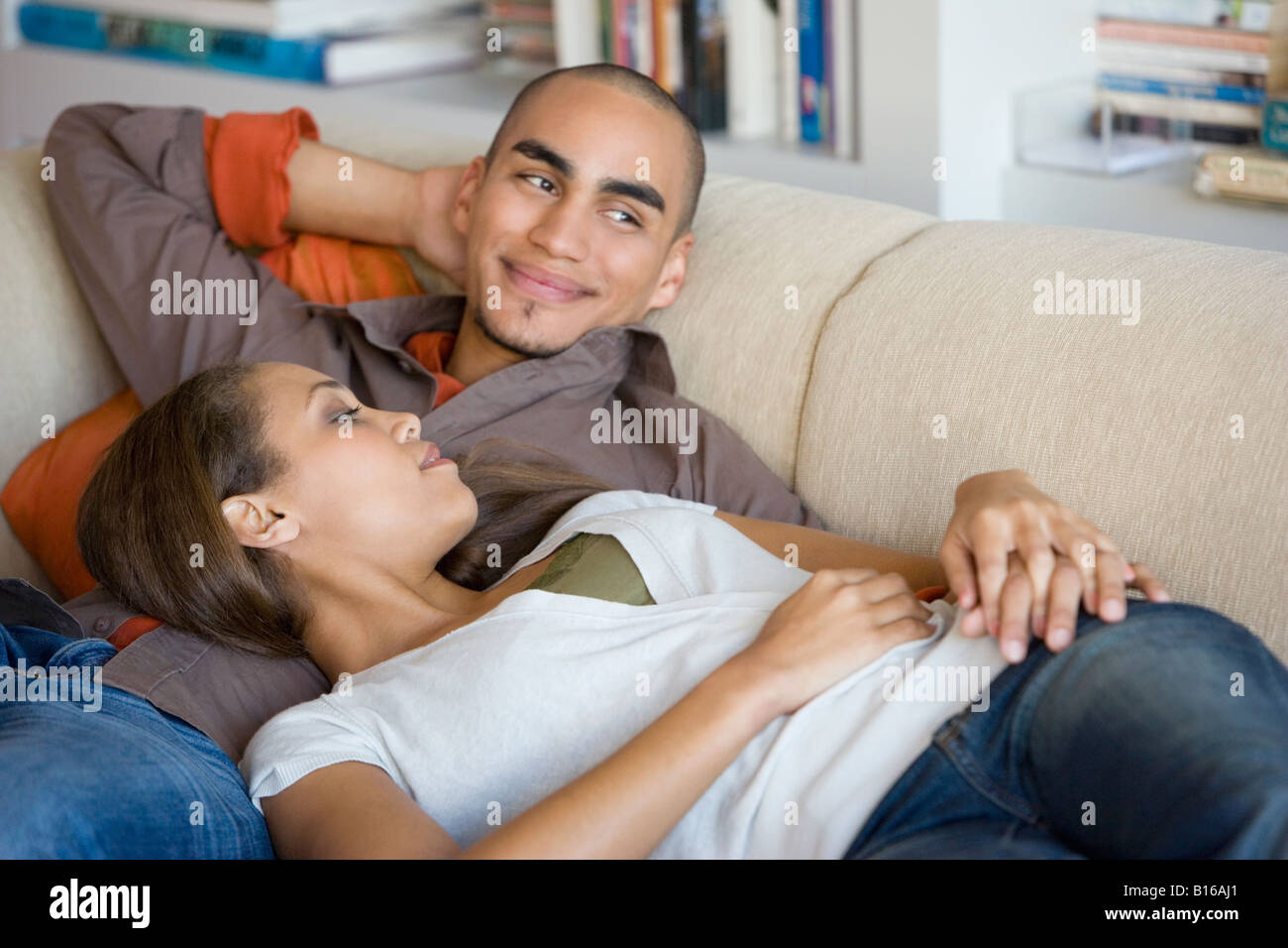 African American couple laying on sofa Stock Photo - Alamy