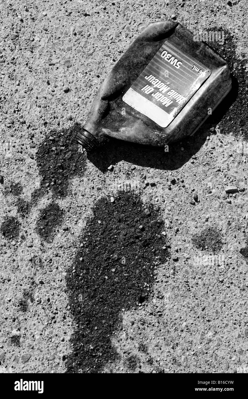 A squashed motor oil bottle spills its contents on the pavement Stock Photo