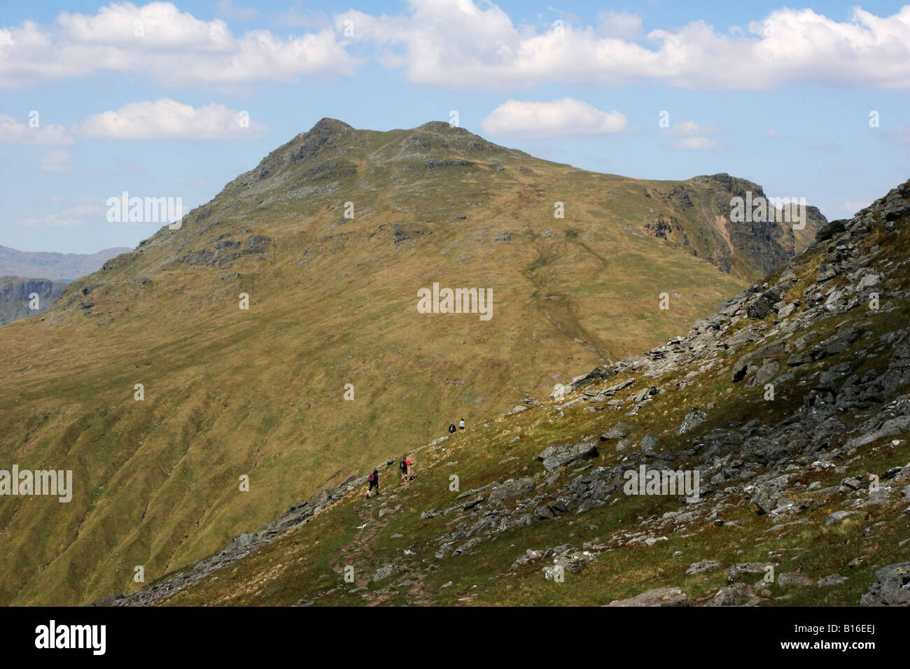 Hillwalkers decending the path on Ben Arthur The Cobbler with Beinn Ime in the background Stock Photo