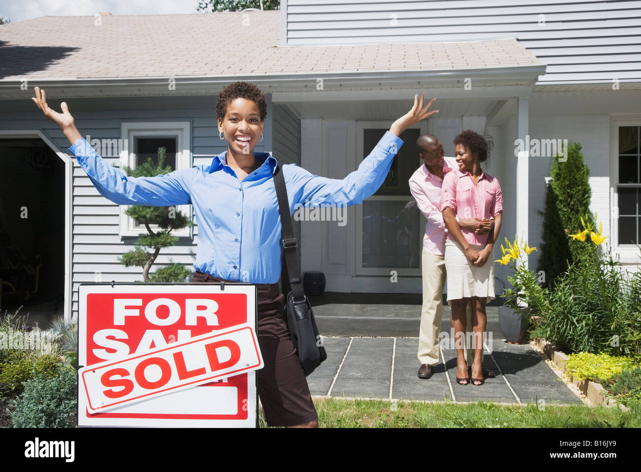 African American real estate agent and couple in front of new house