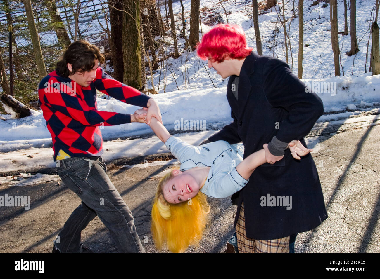Teen boys one with dyed red hair joking around outside with a blond teen girl Model Released Stock Photo