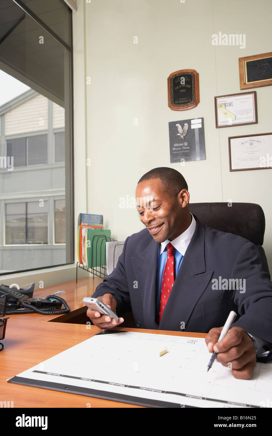 African businessman looking at electronic organizer Stock Photo