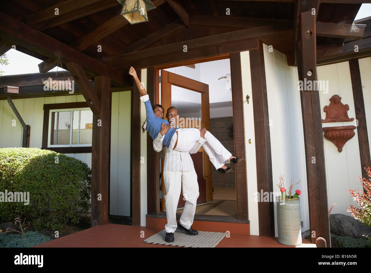 African man carrying wife in doorway Stock Photo
