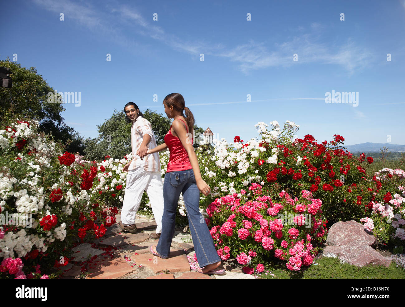 Multi-ethnic couple walking through garden Stock Photo