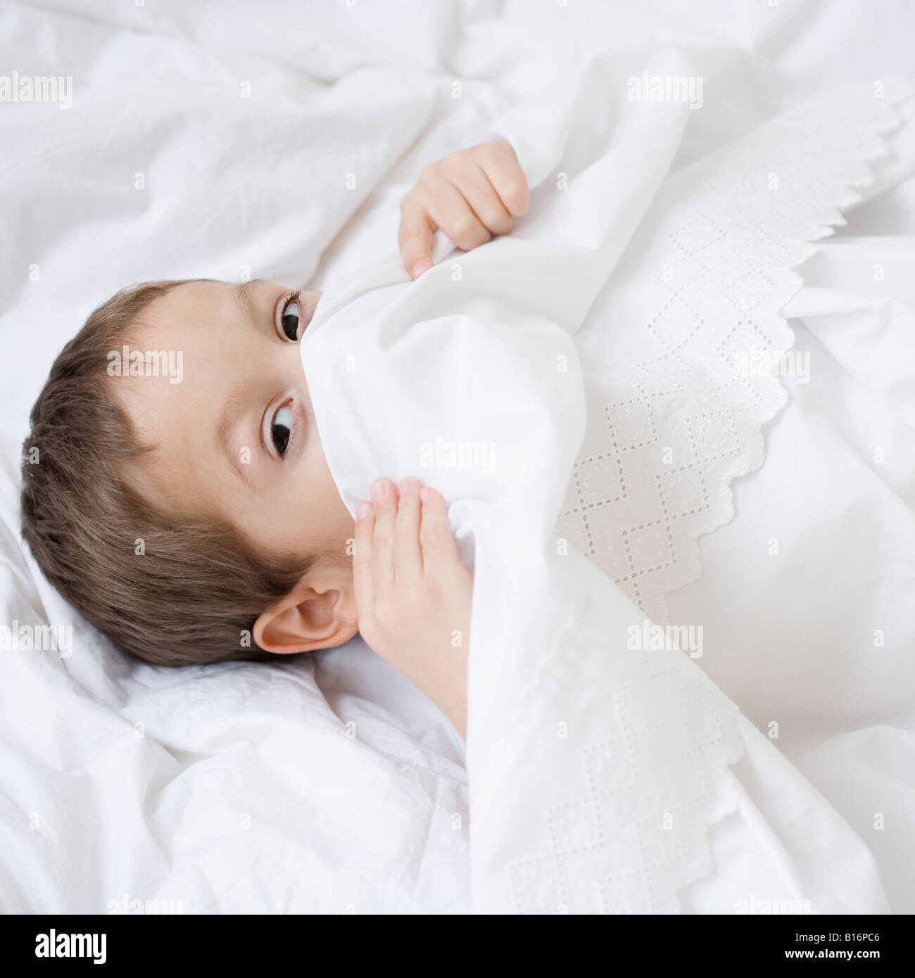 Hispanic boy hiding under covers Stock Photo Alamy