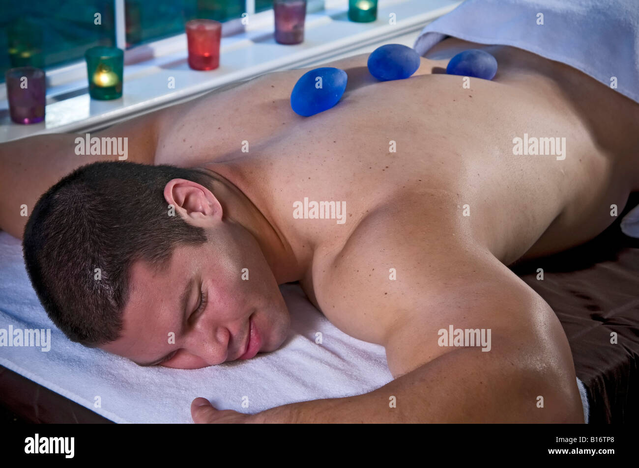 A very muscular man lying face down on a massage table. Stock Photo