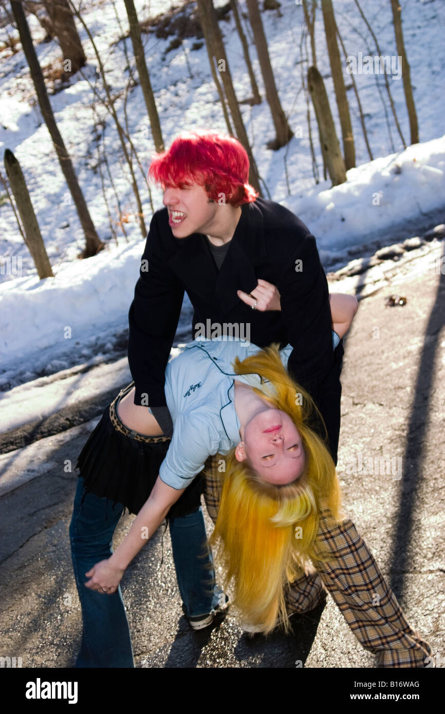 Teen boy with dyed red hair joking around outside with his blond girlfriend Model Released Stock Photo
