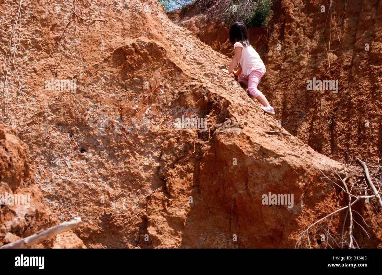A four year old girl climbing a small hill. Stock Photo
