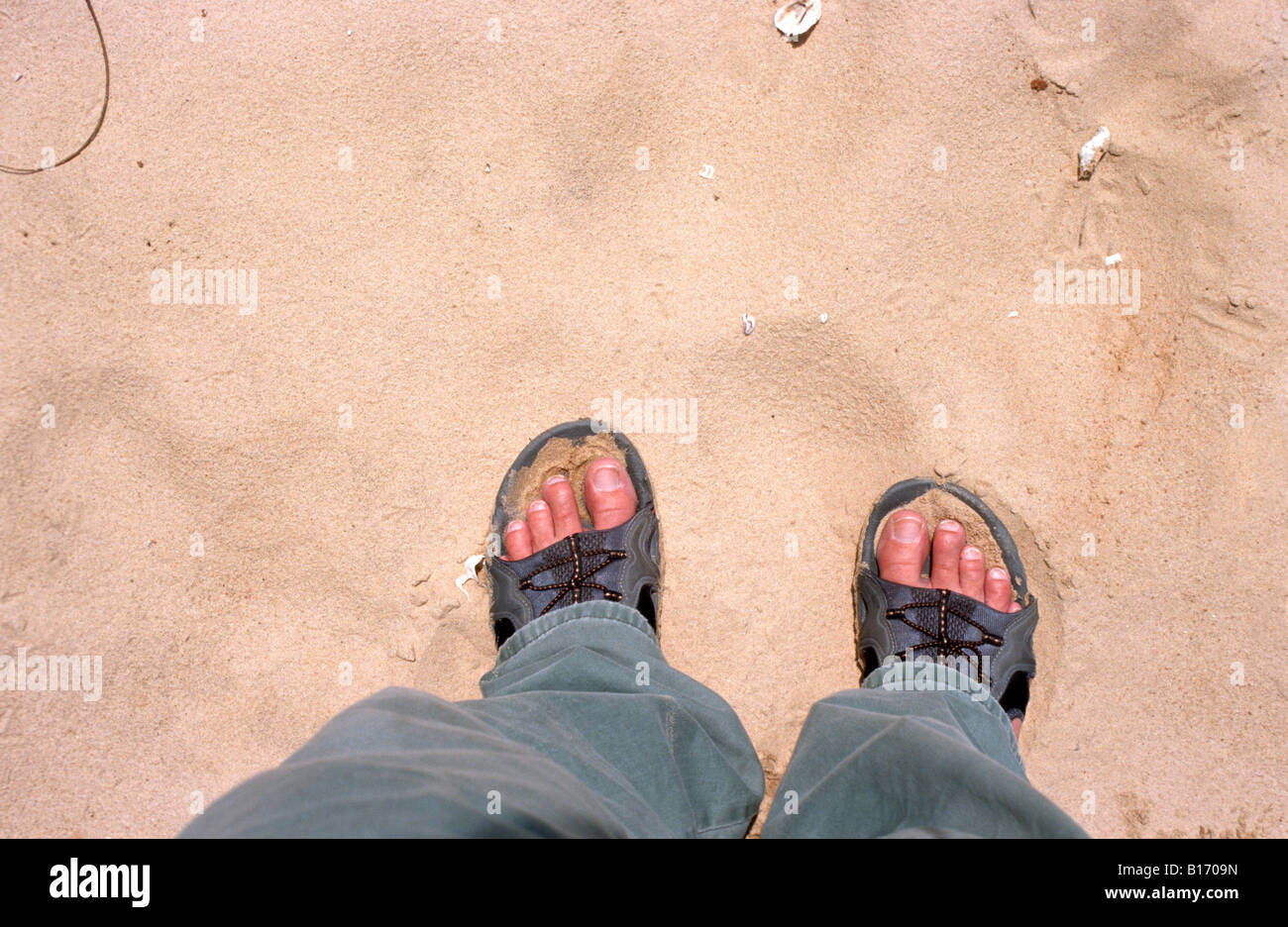 Feet of man standing in dry sand Stock Photo